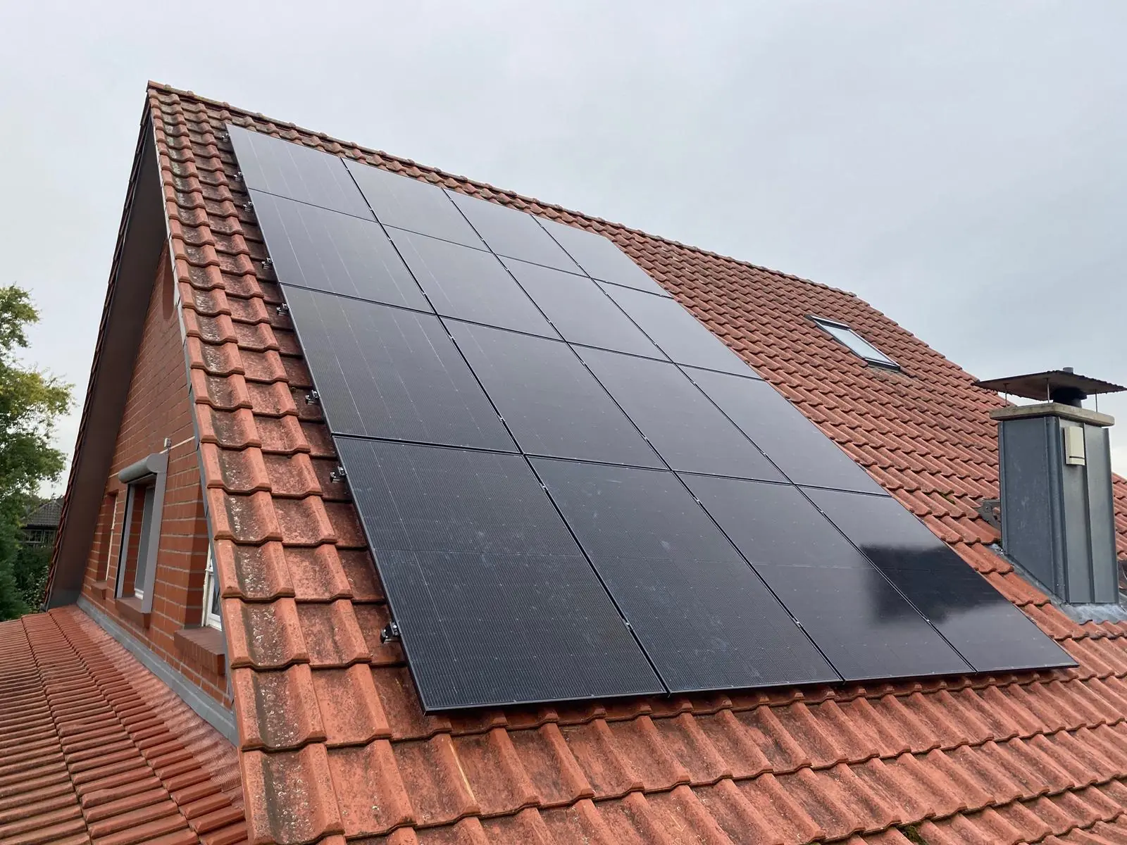 Schwarze Photovoltaikmodule auf einem roten Ziegeldach
