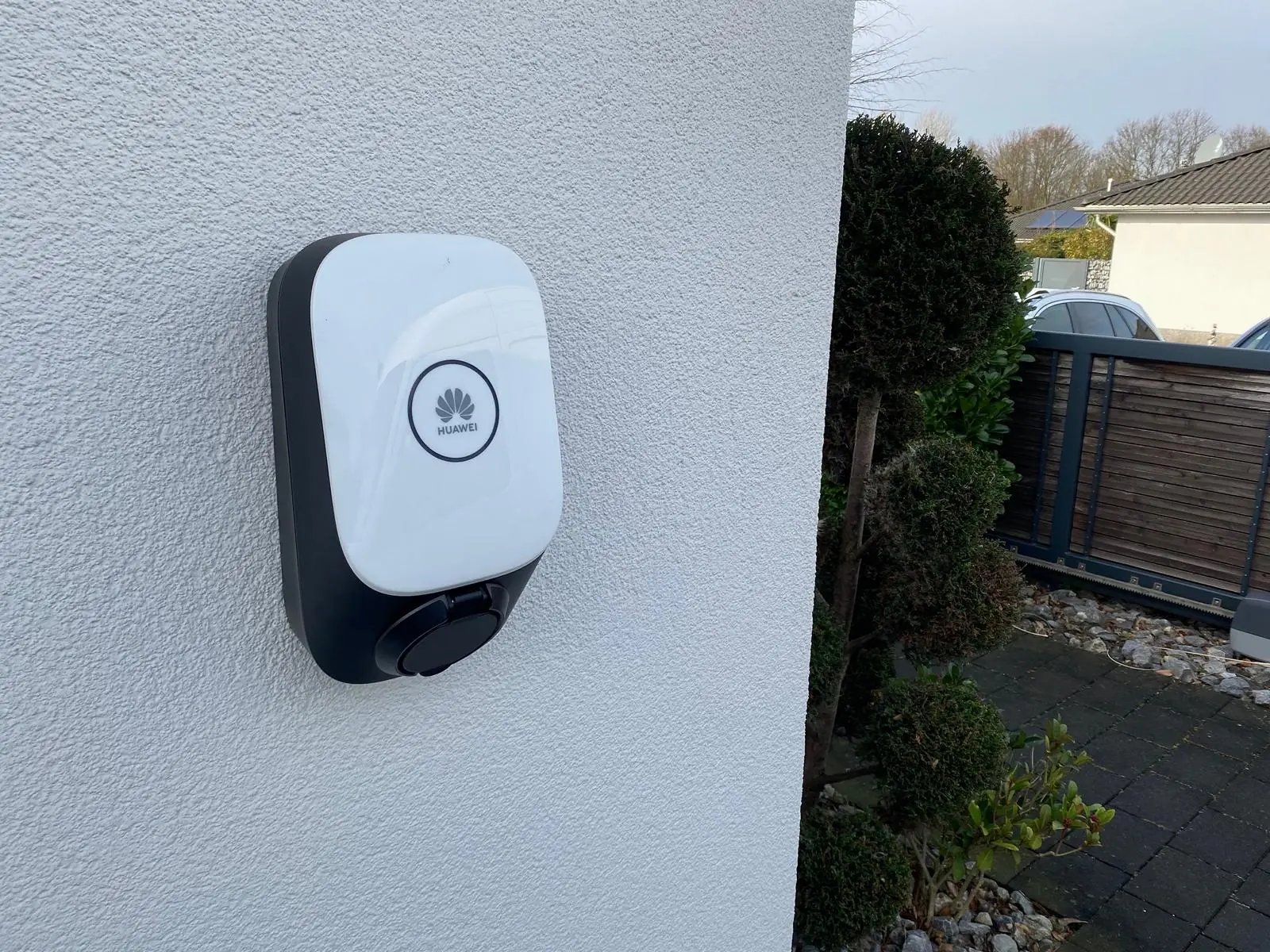 Wallbox an einer verputzten Hauswand neben der Einfahrt